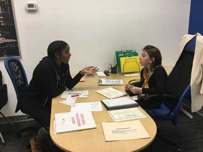 Shawna Thomas sits with a JA student to explain a task.