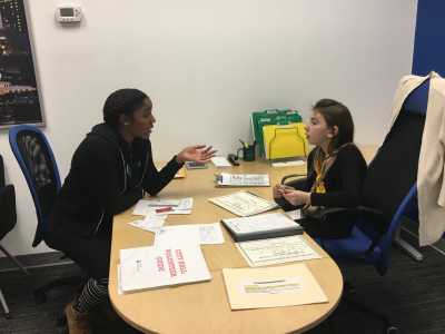 Shawna Thomas sits with a JA student to explain a task.