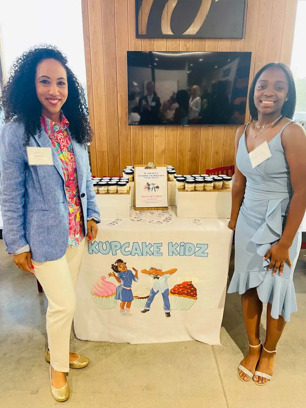 Professional and student stand next to the student's table featuring their business.
